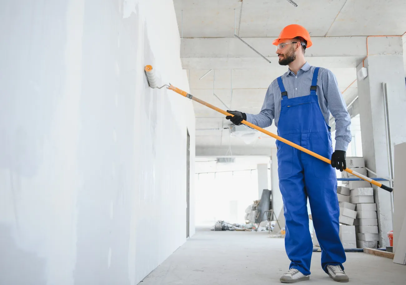 Maler streicht eine Innenwand mit der Rolle